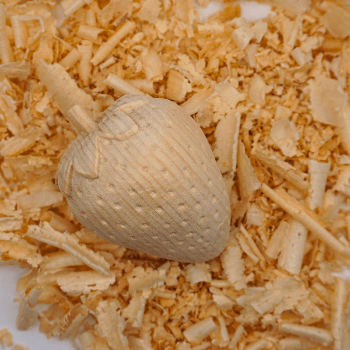 Dekorative Holzfigur in Erdbeerform von oben auf Holzspänen.