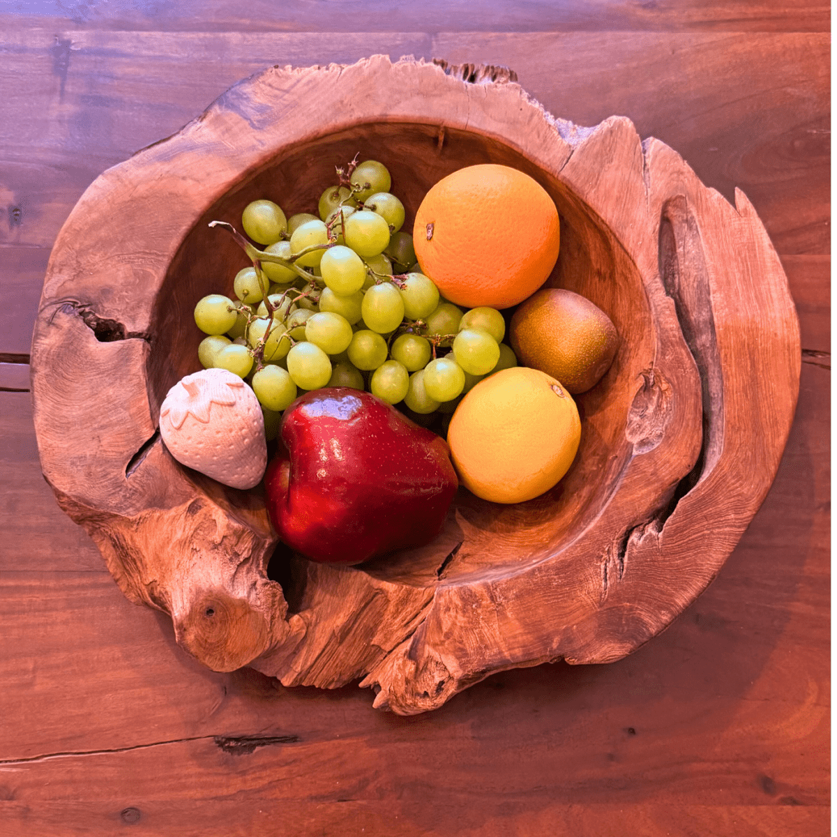 Obst und dekorative Holzfrüchte gemeinsam in einer rustikalen Holzschale.