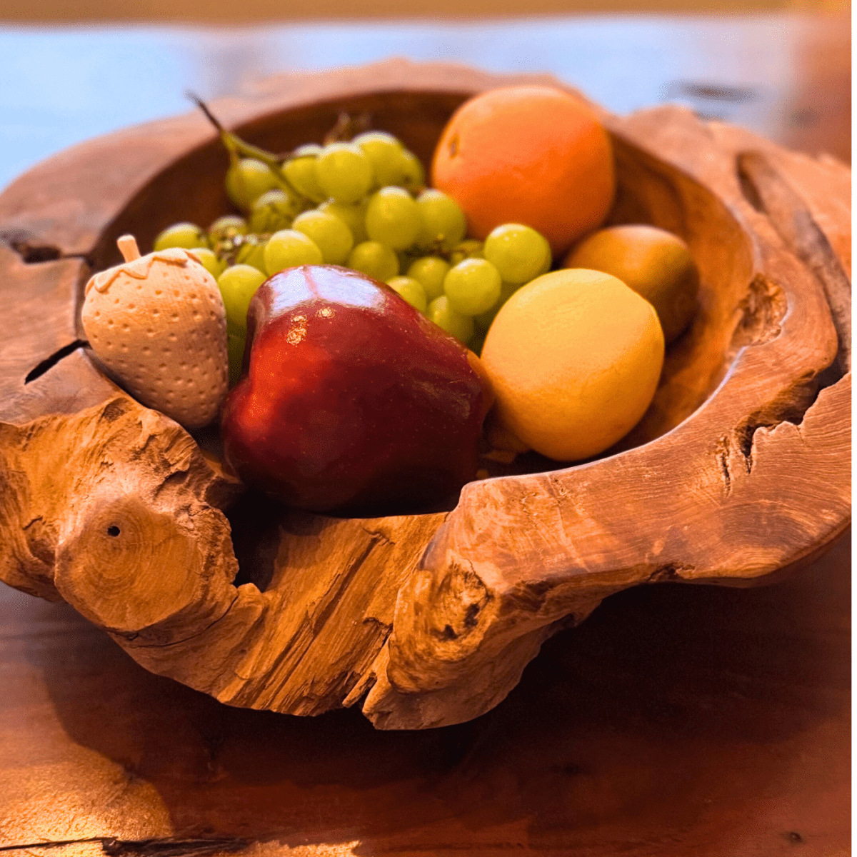 Obst und dekorative Holzfrüchte gemeinsam in einer rustikalen Holzschale.