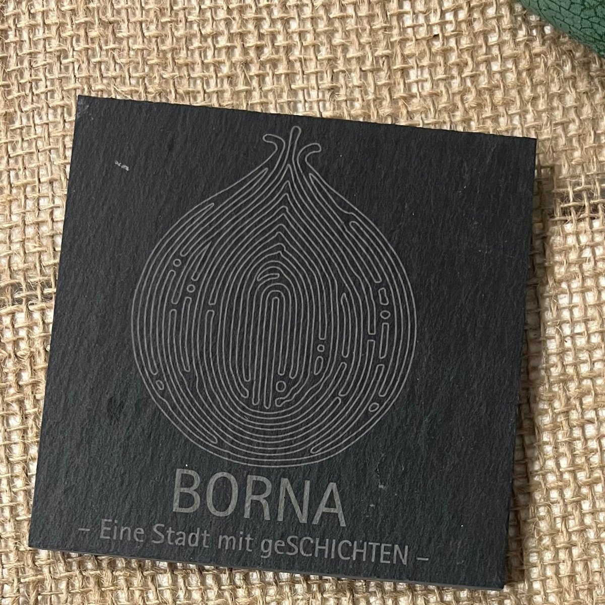 Quadratischer Schieferuntersetzer: Borna-Fingerprint-Motiv und Stadtschriftzug.