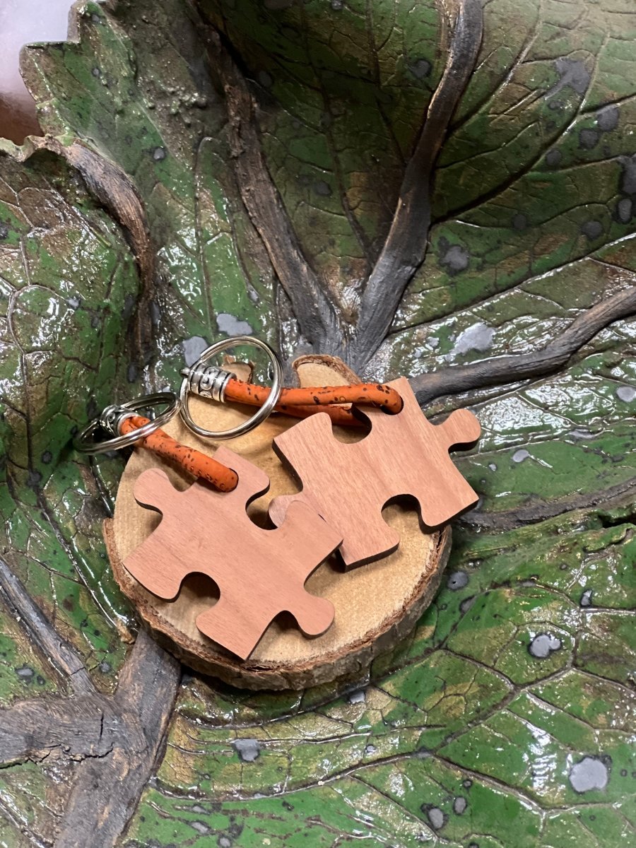 Schlüsselanhänger Puzzle aus Holz: zwei Puzzleteile auf einer Holzscheibe.