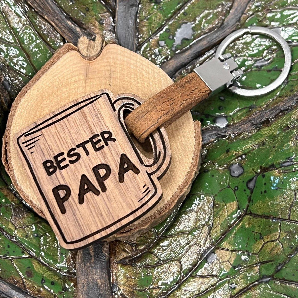 Holz-Schlüsselanhänger: tassenförmiges Holzmotiv „Bester Papa“ auf einer Holzscheibe.