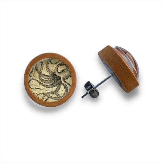 Ein Paar runde Holzohrstecker mit Birkenholzkanten und klaren Cabochons zeigen eine Krakenillustration auf Beige. Ein Ohrring ist flach, der andere liegt auf der Seite. Marke: Holzohrstecker.