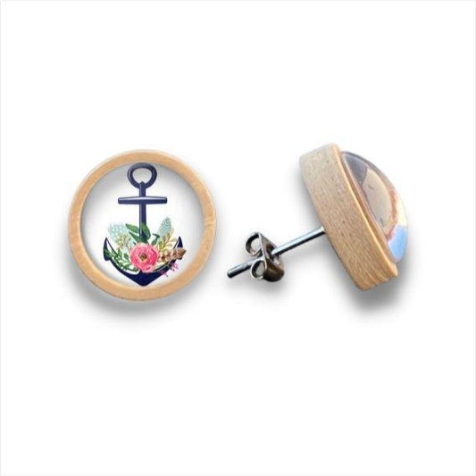 Ein Paar runder Holzohrstecker mit hellen Birkenkanten, jeder Ohrring präsentiert einen marineblauen Anker mit bunten Blumen unter einer glänzenden Cabochon-Kuppel.