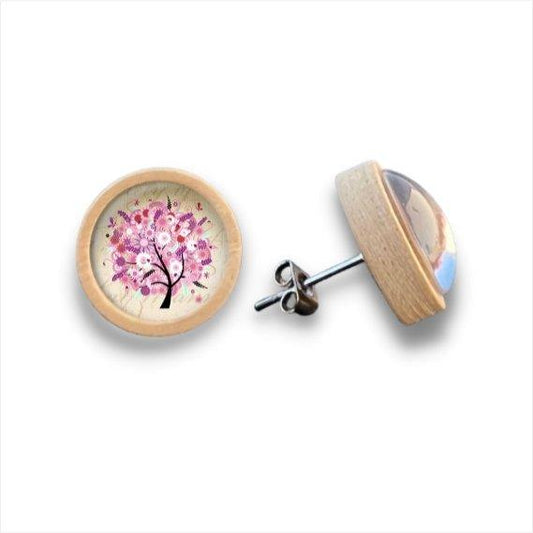 Ein Paar runder Holzohrstecker mit hellen Birkenholzrahmen, die eine rosa blühende Baumillustration auf cremefarbenem Hintergrund unter klarem Cabochonglas zeigen. Ein Ohrring ist nach vorne gerichtet; der andere zeigt die Seite und den Stift.