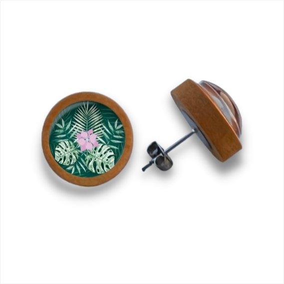 Ein Paar runder Holzohrstecker aus Birkenholz mit einem botanischen Muster aus grünen tropischen Blättern und einer rosa Blume unter klarem Cabochonglas; ein Ohrring zeigt nach oben, der andere zeigt seine Seite und den Metallstift auf weißem Hintergrund.
