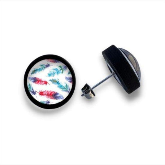 Ein Paar runde Ohrstecker aus Holz mit schwarzer Umrandung, die ein farbenfrohes Federmuster in Blau, Lila, Rot und Grün unter einer Cabochonglaslinse auf weißem Hintergrund zeigen.