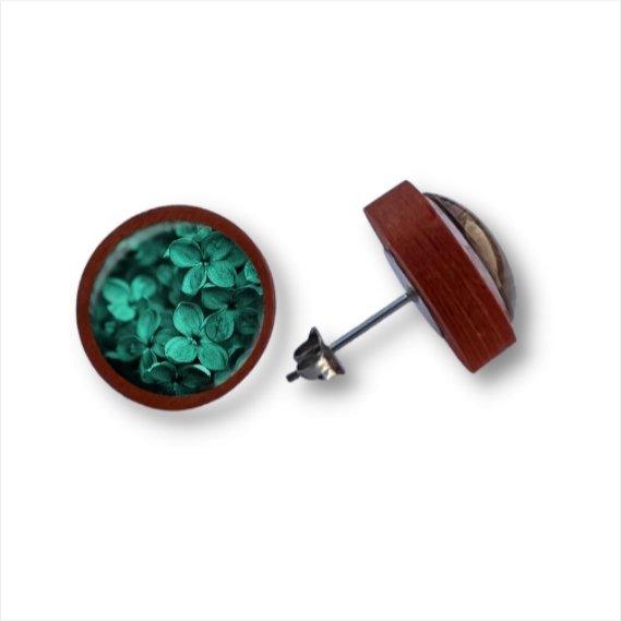Ein Paar runder Holzohrstecker mit Birkenholzkanten und einer Cabochon-Glaskuppel mit winzigen türkisfarbenen Blütenblättern im Inneren, abgebildet auf einem weißen Hintergrund.