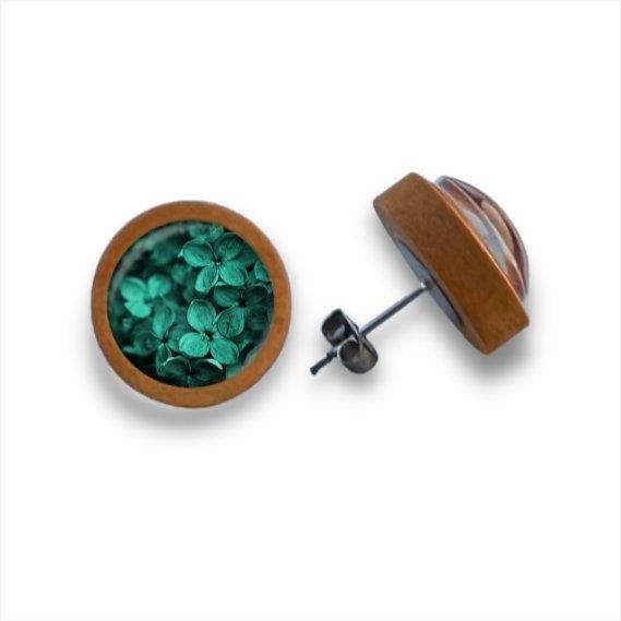 Ein Paar runde Holzohrstecker von Wood Stud, gefertigt aus Birkenholz mit klaren Cabochon-Glaskuppeln, die zarte grüne Trockenblumen umhüllen und auf einem weißen Hintergrund wunderschön zur Geltung kommen.