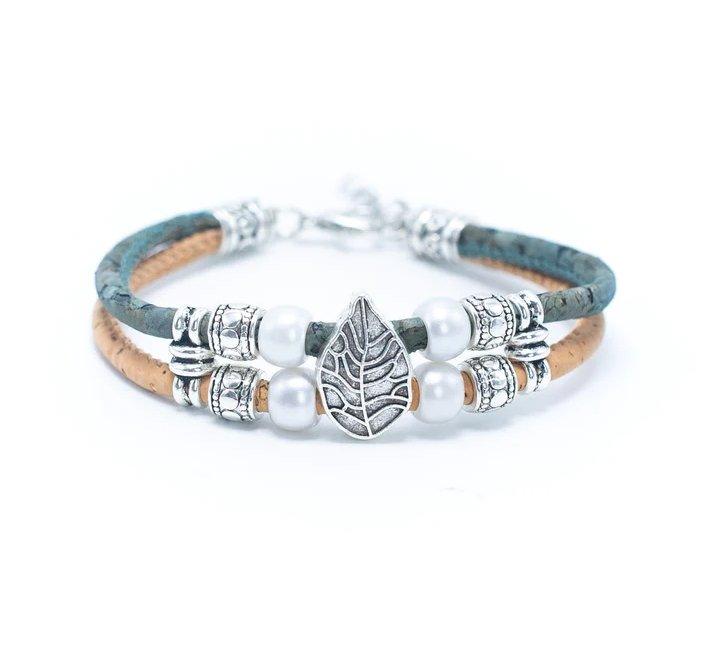 Ein doppelreihiges Kork-Armbänder-Armband von Wood Stud mit hellgrünen und hellbraunen Bändern, silbernen Zierperlen, weißen Perlen und einem silbernen Blattanhänger in der Mitte. Diese nachhaltige, nickelfreie Stück ist auf einem weißen Hintergrund angezeigt.