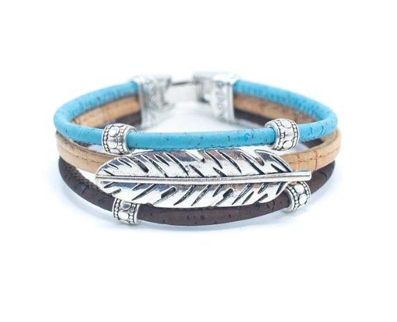 Das Holzstollen Kork-Armband-Set besteht aus drei nachhaltigen Bändern in Blau, Beige und Braun mit silberner Feder und nickelfreien Edelstahlakzenten.