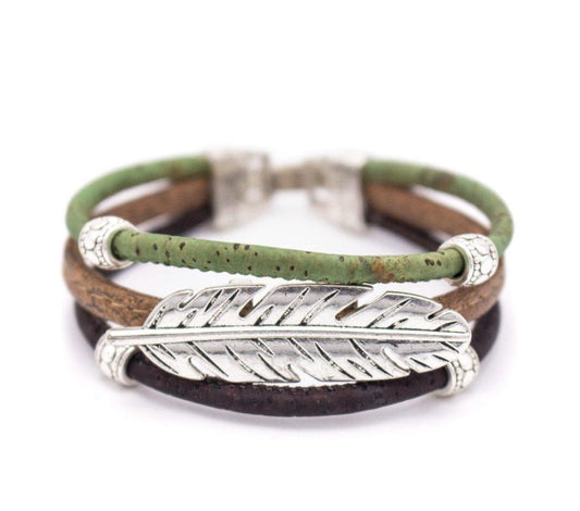 Das nachhaltig gefertigte Kork-Armband von wood stud mit drei Bändern in Grün, Braun und Dunkelbraun verbindet eine Silberfeder sowie nickelfreie Edelstahl-Akzente.