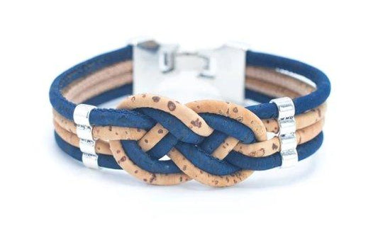 Das nachhaltige Kork-Armbänder mit Holzstollen zeigt blaue und hellbraune Korkschnüre in einem Knoten, silberne Akzente aus nickelfreiem Edelstahl und einen rechteckigen Verschluss, alles auf weißem Hintergrund.