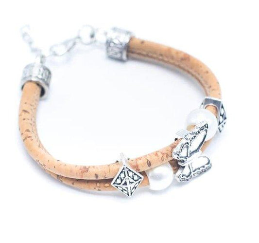 Ein Holzarmband mit zwei hellbraunen Kork-Armbändern, silbernen Zierperlen, einer weißen perlenartigen Perle und einem nickelfreien Schmetterlingsanhänger aus Edelstahl auf weißem Hintergrund.
