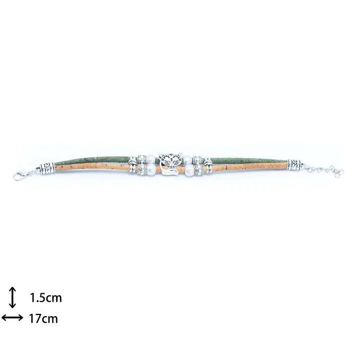 Das mehrreihige Korkarmband mit Holzstiften hat grüne und hellbraune Bänder, silberfarbene Perlen, einen zentralen Baumanhänger, ist umweltfreundlich und nickelfrei und misst 17 cm lang und 1,5 cm breit.