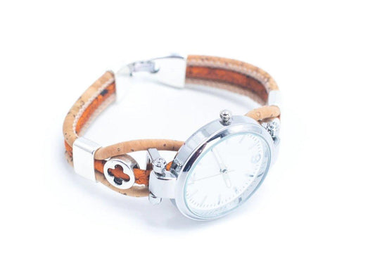 Eine Holzknopfarmbanduhr mit einem runden silbernen Gehäuse, hellbraunem Lederband aus nachhaltigen Materialien und einem kleinen kleeblattförmigen Metalldetail, abgebildet auf einem weißen Hintergrund.