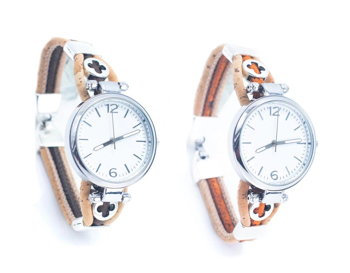 Zwei Holzbolzen-Armbanduhren mit weißen Ziffernblättern, silbernen Gehäusen und hellbraunen Lederbändern mit dekorativen Aussparungen, hergestellt aus nachhaltigen Materialien, auf weißem Hintergrund.