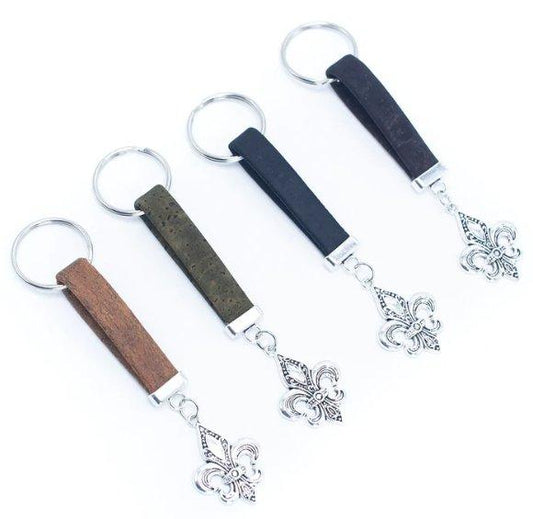 Set mit vier Schlüsselanhängern aus Holz mit Metallringen, jeweils in braun, olivgrün, schwarz und dunkelbraun aus veganem Kork. Jeder hat einen silbernen Fleur-de-Lis-Anhänger - eine nachhaltige, umweltfreundliche Alternative zu herkömmlichen Schlüsselanhängern.