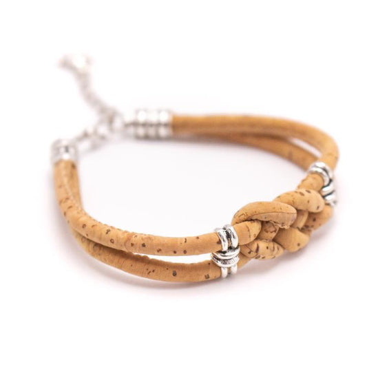Ein hellbraunes Holzarmband mit zwei Bändern, nickelfreien Edelstahl-Akzenten und einem zentralen Knotenmuster auf weißem Hintergrund.