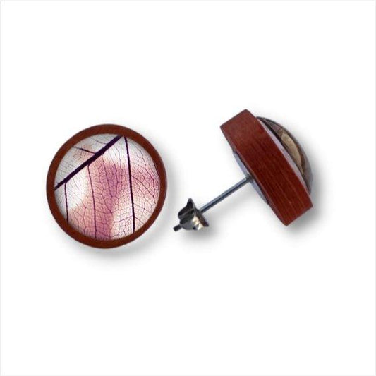 Ein Paar handgefertigte Ohrstecker aus Holz mit einer Cabochon-Glaslinse, die ein zartes rosafarbenes Blattmuster mit feinen Adern auf weißem Hintergrund zeigt, eingefasst in einen runden Holzrahmen.