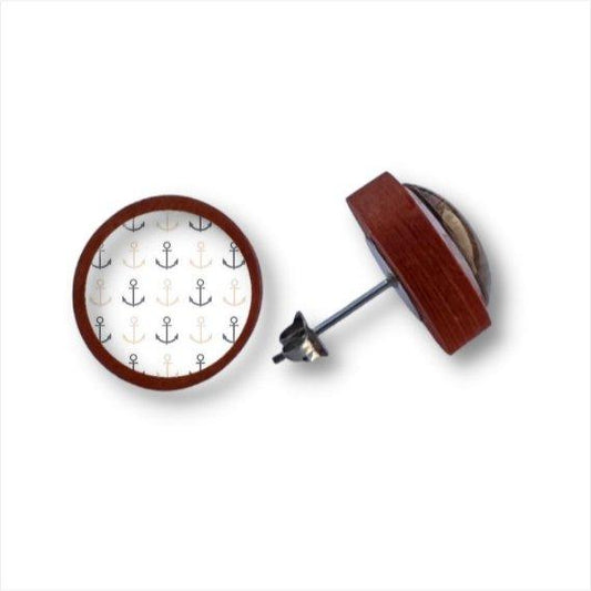 Ein Paar runder Holzohrstecker mit braunen Birkenholzrändern und einem Muster aus schwarzen, goldenen und silbernen Ankern auf weißer Cabochon-Glaslinse. Ein Ohrring ist mit der Vorderseite nach oben, der andere ist auf der Seite abgebildet.