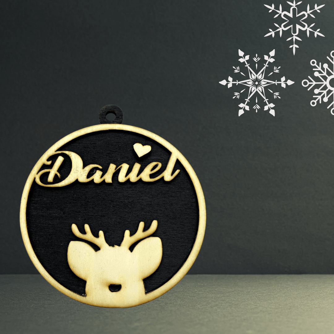 Holzständer 3D-Holz-Weihnachtskugel mit Name Daniel im Schreibschrift-Design über Rentiersilhouette, goldumrandet, auf dunklem Hintergrund mit weißen Schneeflocken. Personalisierbarer Anhänger.