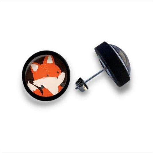 Ein Paar runder Holzohrstecker mit einem charmant illustrierten orangefarbenen Fuchs mit weißen Akzenten auf schwarzem Hintergrund. Ein Ohrring zeigt nach vorne; der andere zeigt seine Metallstange und Cabochon-Glaslinse.