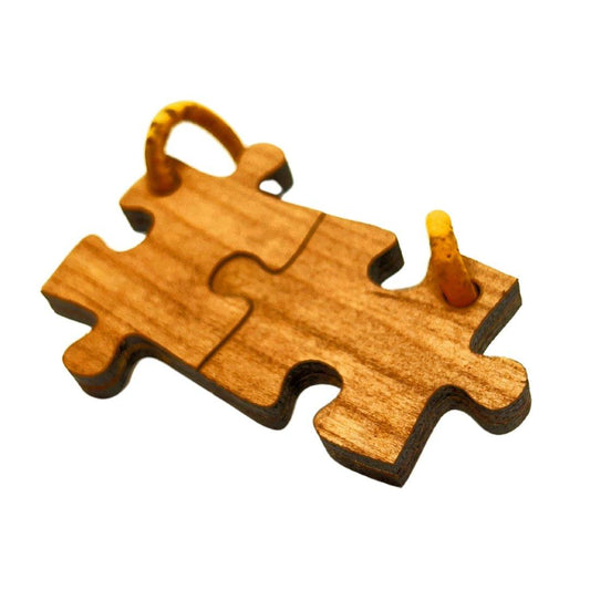 Zwei ineinander greifende Holzpuzzleteile von Wood Stud, an denen jeweils eine gelbe Metallschlaufe befestigt ist, zeigen ihre natürliche Maserung und ihr nachhaltiges Design auf einem weißen Hintergrund.
