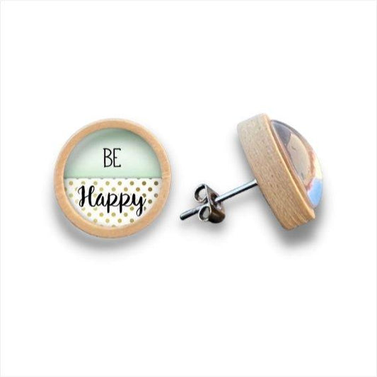 Ein Paar runde Ohrstecker aus Holz mit Birkenholzkanten. Auf der Vorderseite steht "BE Happy" in schwarzer Schrift auf weißem und goldenem Tupfenhintergrund, gekrönt von einer klaren Cabochon-Glaskuppel.