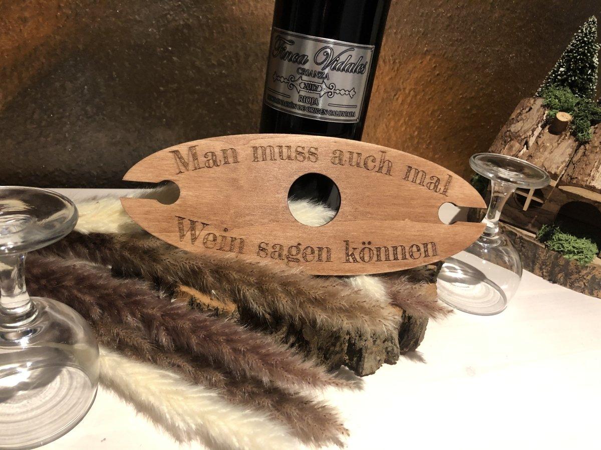 Ein hölzerner Wein-Butler mit der Aufschrift "Man muss auch mal Wein sagen können" sitzt neben zwei leeren Weingläsern und einer Weinflasche - das ideale Geschenk für jeden Weinliebhaber.