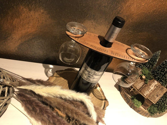 Der wood stud Wein-Butler präsentiert eine Flasche Wein und zwei kopfüber balancierende Gläser aus Holz - ein stilvolles Geschenk für Weinliebhaber, ideal neben Trockenblumen und einem Modellhaus dekoriert.