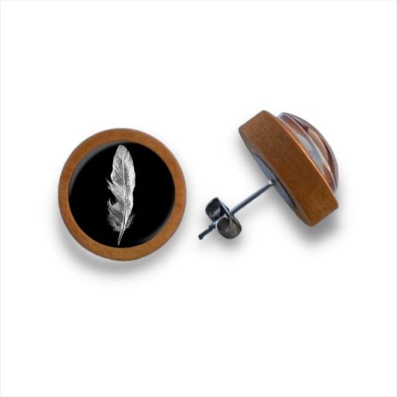 Runde Holzohrstecker mit Kanten aus Birkenholz und einem schwarzen Cabochon-Glas in der Mitte mit einem weißen Federmotiv. Das Bild zeigt einen Ohrring in der Vorderansicht, den anderen in einem Winkel, um die Seite und den Stift zu zeigen.