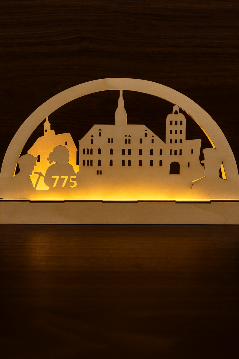 Die in Thüringen handgefertigte Holzständersilhouette zeigt Gebäude und zwei Figuren mit "775" und warmer Hintergrundbeleuchtung - eine Sonderedition 775 Jahre Borna - vor dunklem Hintergrund.